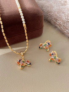 Close-up of golden horse-shaped pendant and earrings with colorful stones and pearls