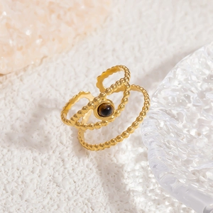 Macro detail of 18k gold stacked ring featuring beaded texture and brown gemstone