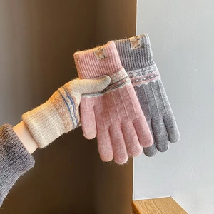 Close-up of thick knitted gloves in pink, grey and beige with soft warm thermal lining