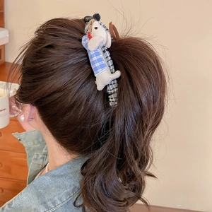 Detailed view of plush dachshund bow hair clip worn on person, showing checkered fabric texture