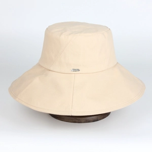 Detail of wide brim beige bucket hat with metallic logo and sturdy cotton fabric