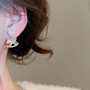 Detailed close-up of a rocking horse pearl earring with pink and blue enamel finish