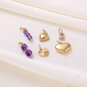 Detailed collection of vintage heart-shaped gold pendants with purple gems on white fabric