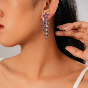 Close-up of model wearing purple vintage glass flower and leaf tassel drop earrings