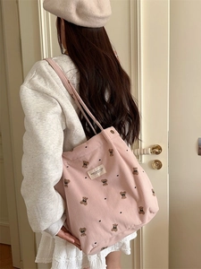 Pink corduroy tote bag with bear embroidery shown in a stylish lifestyle casual setting