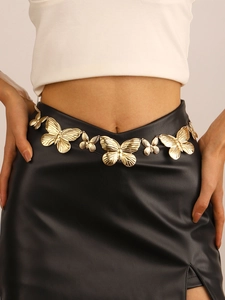 Close-up of a golden butterfly waist chain with carved textures on a black skirt