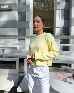 Detail view of pale yellow knit sweater with side slit hem and crew neck design