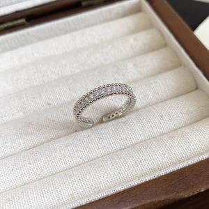 Detailed view of silver open ring with pave-set zircons in a beige linen jewelry box
