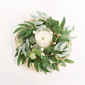 Macro view of eucalyptus leaf candle ring with white pearls on a woven straw mat