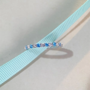 Close-up of S925 silver ring with blue and white zircons on a light blue silk ribbon