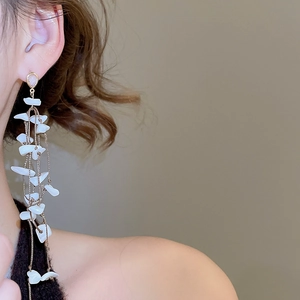 Detailed view of long gold tassel earrings featuring irregular white shell pendants