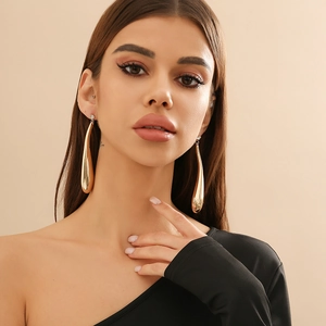Elegant gold teardrop earrings with sparkling rhinestones worn by a model