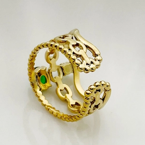 Detailed close-up of a gold chain ring featuring a green gemstone and beaded edges