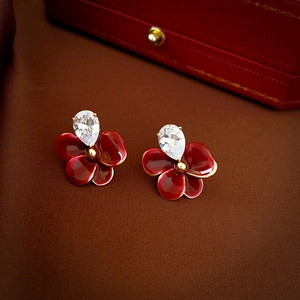 Détail de boucles d'oreilles fleur en émail rouge et zircon sur une boîte à bijoux