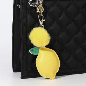 Faux rabbit fur yellow pompom keychain with lemon PU leather leaf on a black quilted bag