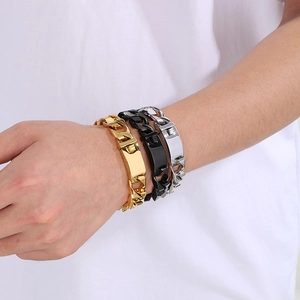 Gros plan de bracelets gourmette or, noir et argent avec plaques en métal poli sur le poignet