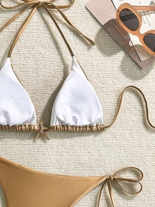 Detalle del top de bikini blanco con hebilla de estrella de mar dorada sobre fondo texturizado