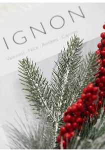 Macro detail of artificial Christmas branch with snowy pine needles and red berries