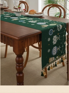 Close-up of green Christmas table runner with festive embroidery and colorful tassels