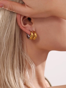 Gros plan de créoles polies en or et argent empilées sur le lobe d'oreille d'un mannequin