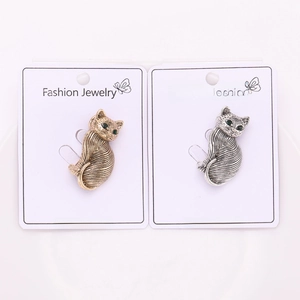 Detail of vintage cat brooches in gold and silver finish with green gemstone eyes