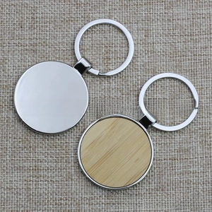 Close-up of round metal and wood inlay keychains on a gray fabric background