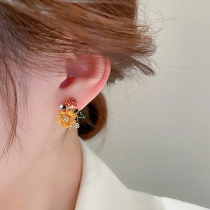 Close-up of flower and fruit stud earring with enamel finish and small crystal