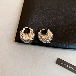 Macro view of silver U-shaped earrings with croissant texture on black leather