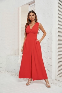 Detail of red sleeveless jumpsuit showing deep V-neck and high waist textured fabric