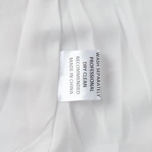 Close-up of the white satin care label with washing instructions on a mini dress