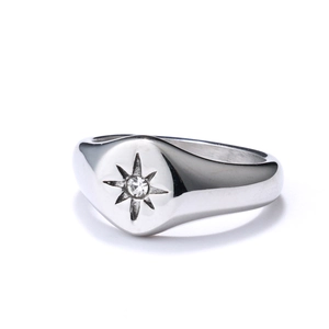 Close-up of a stainless steel signet ring with an engraved starburst and zircon stone