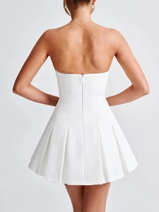 Detail view of the elegant white pleated mini dress showing the hidden back zipper and texture