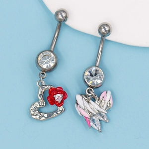 Détail de piercings de nombril en acier avec pendentifs rose et aile et strass roses