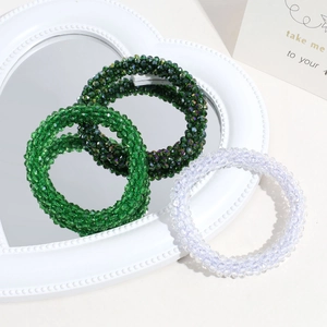 Elegant beaded hair ties in dark green and crystal white on a white heart frame