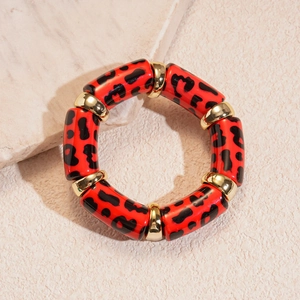 Detailed close-up of acrylic red leopard print bracelet with gold metal beads on marble