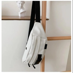 Detail of white canvas waist bag featuring multiple zipper pockets and adjustable black strap
