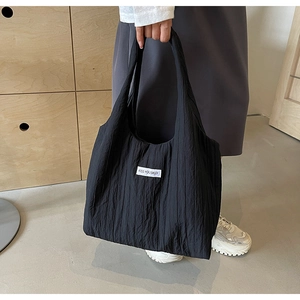 Detail einer schwarzen Nylon-Tragetasche mit Crinkle-Struktur und weißem Textetikett