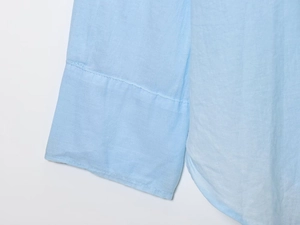 Detailed view of sleeve hem stitching and fabric texture on light blue cotton shirt
