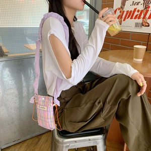 Close-up of a colorful checkered crossbody bag with frilled strap in a cafe setting