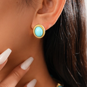 Gros plan sur les boucles d'oreilles ovales dorées torsadées avec turquoise