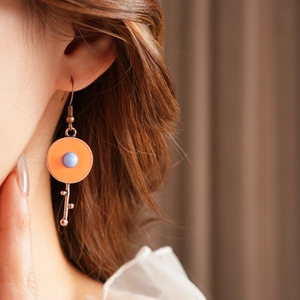 Detail of vintage round enamel drop earrings with blue bead on a female model