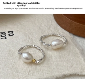 Macro detail of irregular baroque pearl rings with pleated silver texture and metallic beads