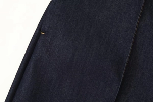 Gros plan sur le tissu denim indigo montrant la texture sergé et les surpiqûres jaunes contrastées