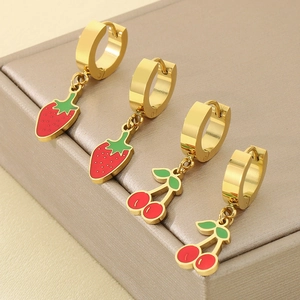 Detail shot of golden strawberry and cherry enamel earrings on a premium jewelry box