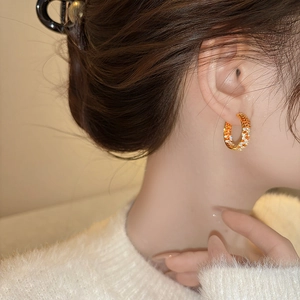 Detail of C-shaped gold hoop earring with pavé-set orange and white cubic zirconia crystals