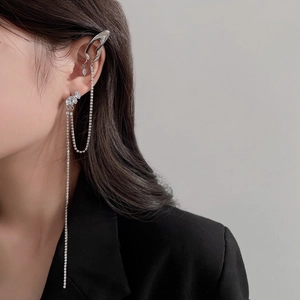 Élégant ear cuff argenté avec nœud et strass porté par un mannequin en costume noir