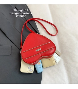 Macro shot of red heart shaped bag showing interior space with phone and wallet