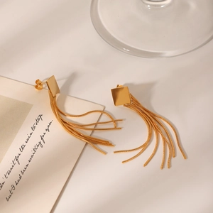 Détail des boucles d'oreilles dorées à pampilles carrées et chaînes serpentines