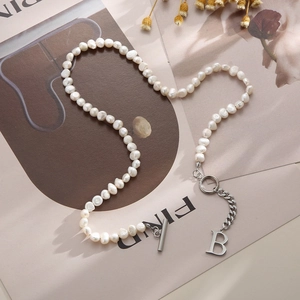 Baroque pearl necklace with silver B letter pendant and toggle clasp on a magazine