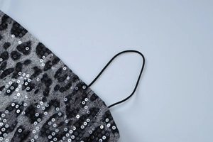 Detail view of leopard print fabric with silver sequins and black elastic straps